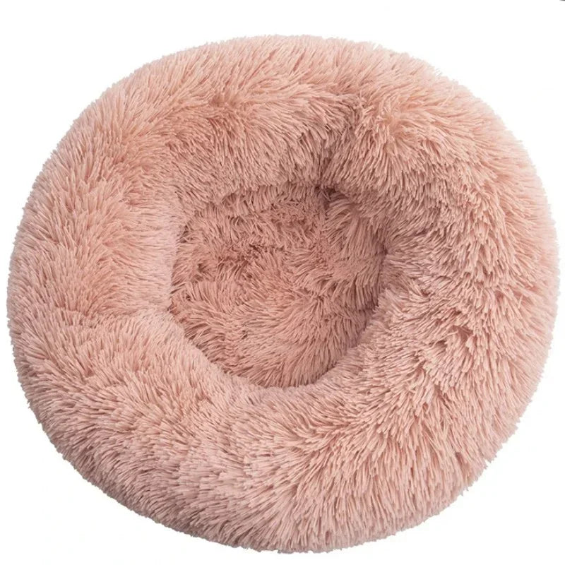 Round fluffy pink pet bed with soft shaggy texture on a white background