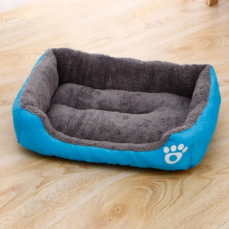 Rectangular blue and gray plush pet bed with paw print, on wooden floor